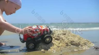 小男孩在沙滩上玩玩具大卡车